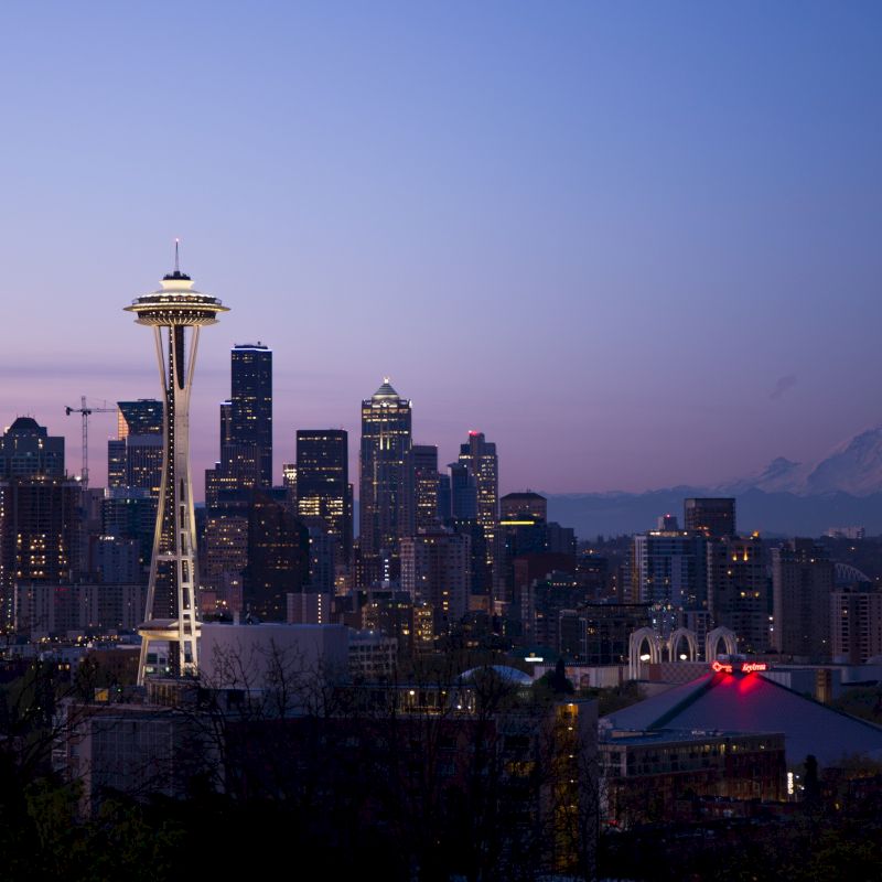 This image shows the Seattle skyline at dusk with the Space Needle prominently featured and Mount Rainier in the background.