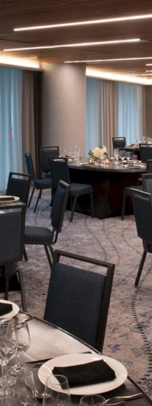A banquet hall with multiple round tables set for a formal event, featuring black tablecloths, elegant place settings, and cream-colored floral centerpieces.